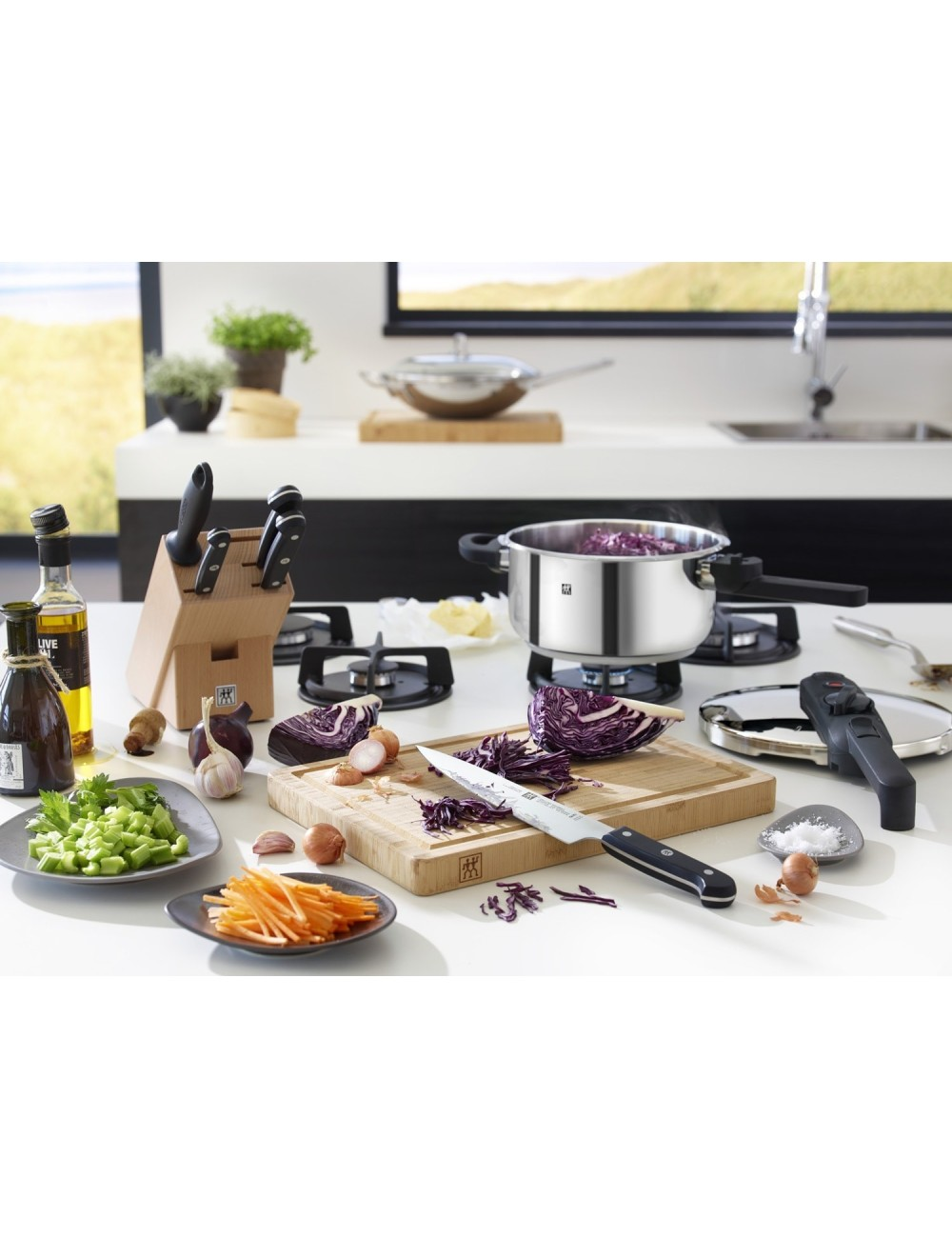 Scena kuchenna z warzywami, nożem, garnkiem i butelkami oleju na białej powierzchni. Garnek gotującej się czerwonej kapusty na kuchence.