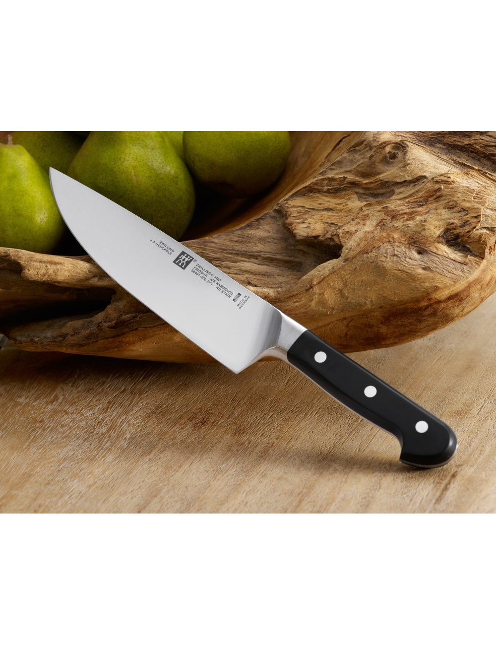 Nóż kuchenny z czarną rękojeścią i trzema nitami spoczywa na drewnianej powierzchni, obok gruszek w drewnianej misce.