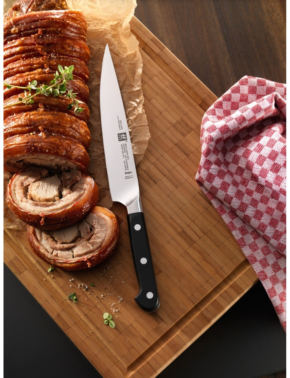 Deska do krojenia z gotowanym mięsem, nożem i czerwoną kraciastą szmatką.