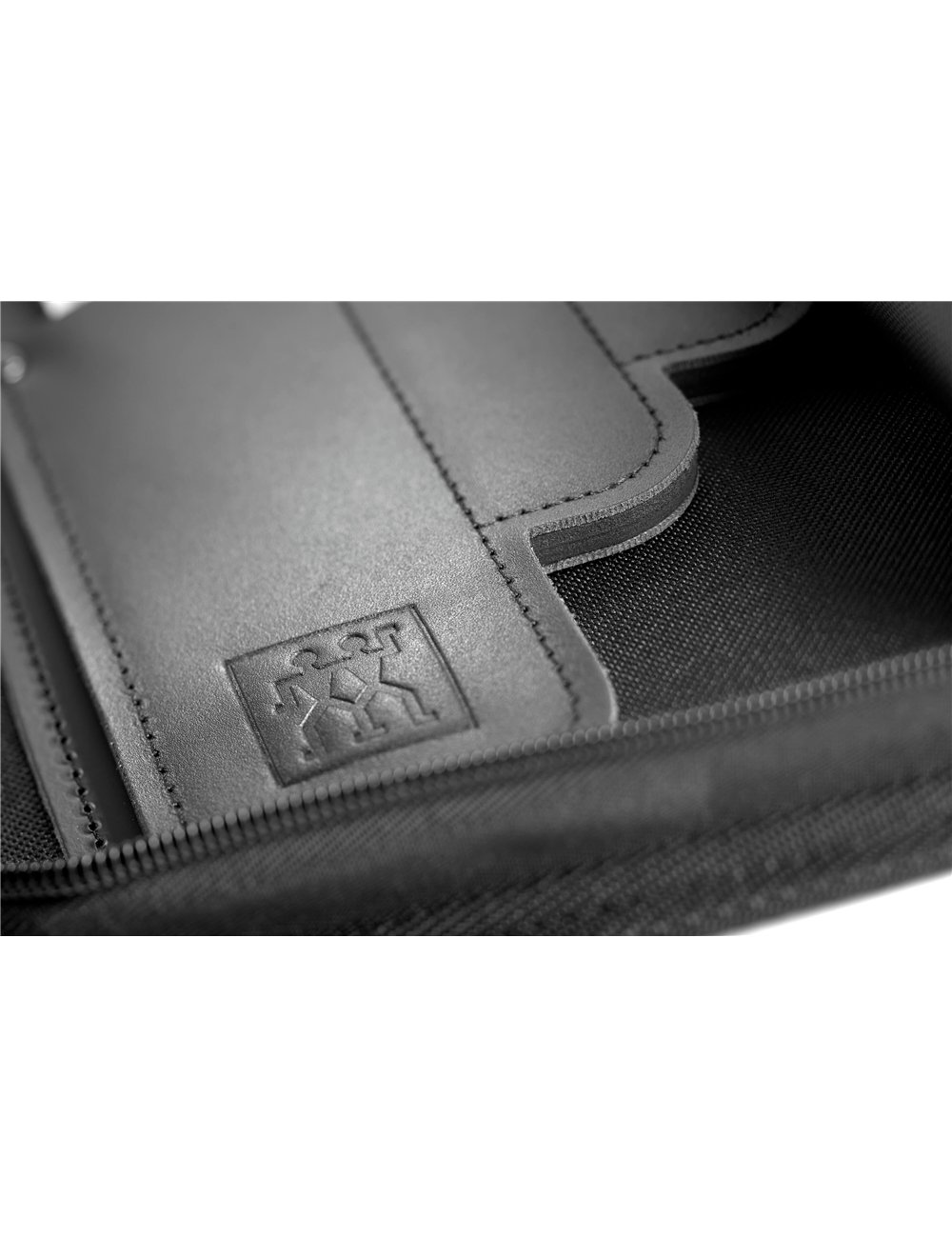 Zbliżenie czarnego skórzanego etui. Ma obszytą krawędź i logo. Tło to czarna, teksturowana tkanina.