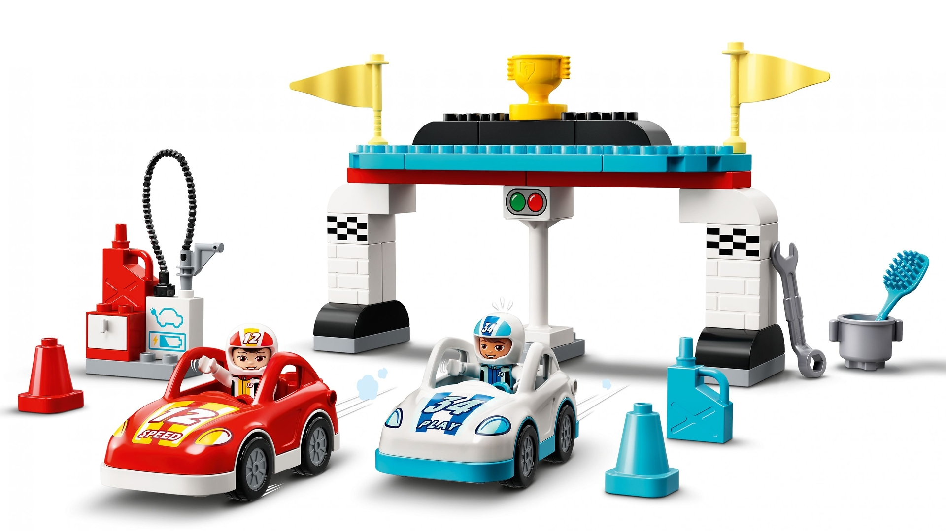 Spielzeug-Rennstrecke mit zwei Autos, Boxenstopp und Ziellinie mit Flaggen und einer Trophäe. Autos sind rot und weiß.