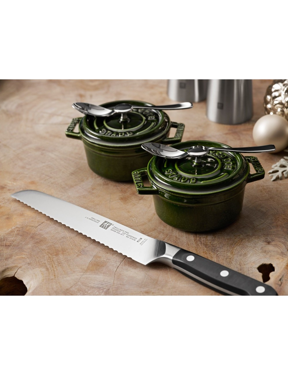 Nóż, dwa zielone garnki z łyżkami i przedmioty dekoracyjne na drewnianej powierzchni.