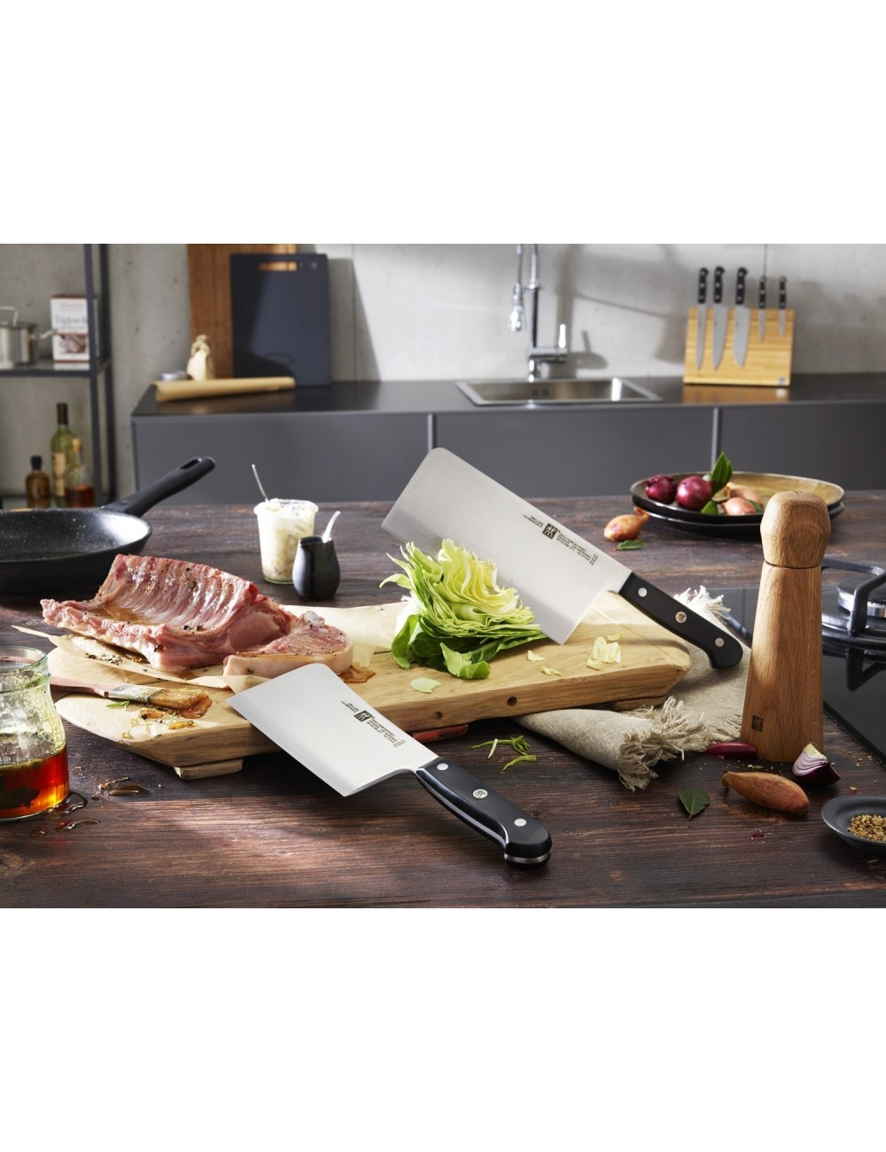 Scena kuchenna z dwoma tasakami, żeberkami i warzywami na drewnianej desce. Tło przedstawia zlew i przybory kuchenne.