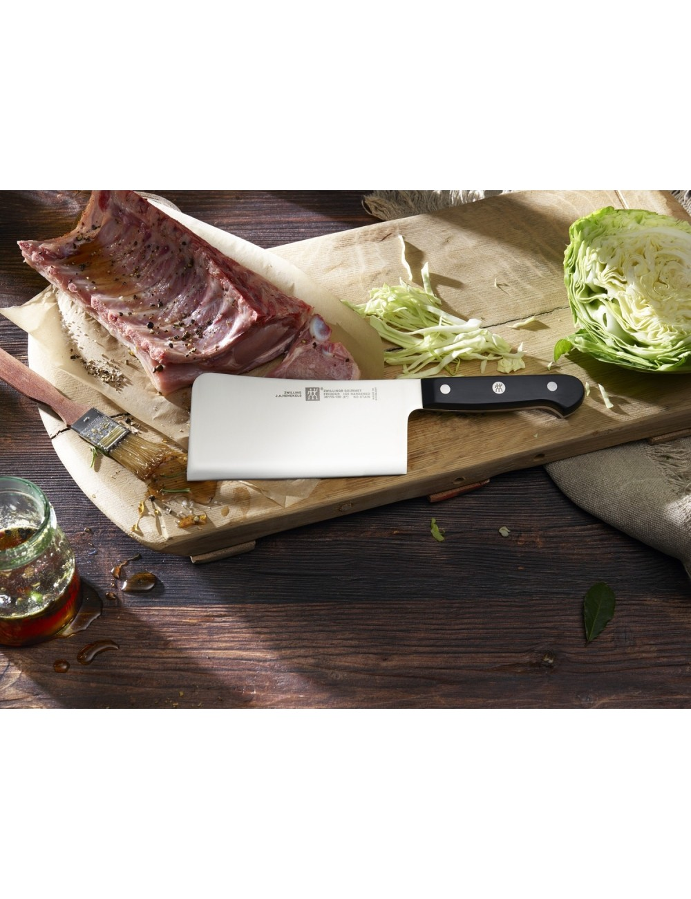 Tasak na drewnianej desce z mięsem, poszatkowaną kapustą i połówką kapusty. Słoik i pędzel po lewej stronie.