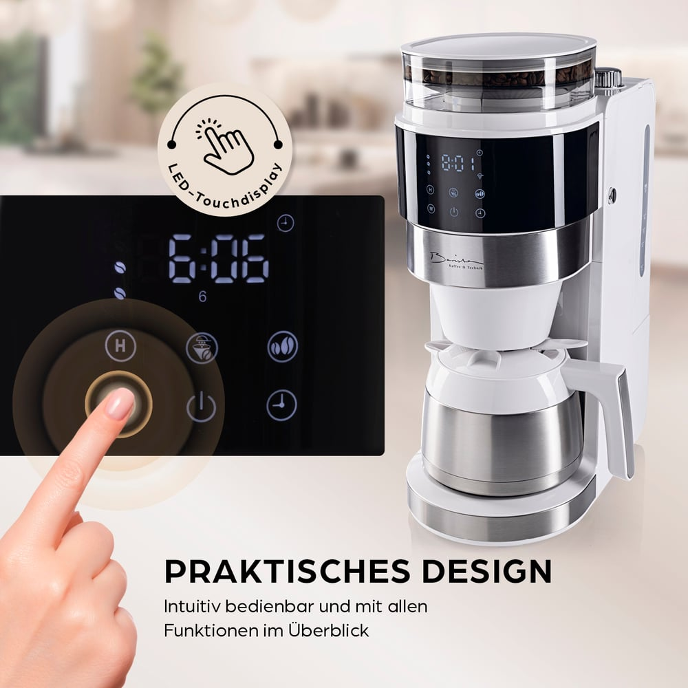 Eine Hand berührt das Touch-Display einer Kaffeemaschine. Das Display zeigt die Uhrzeit. Die Maschine ist weiß und silber.