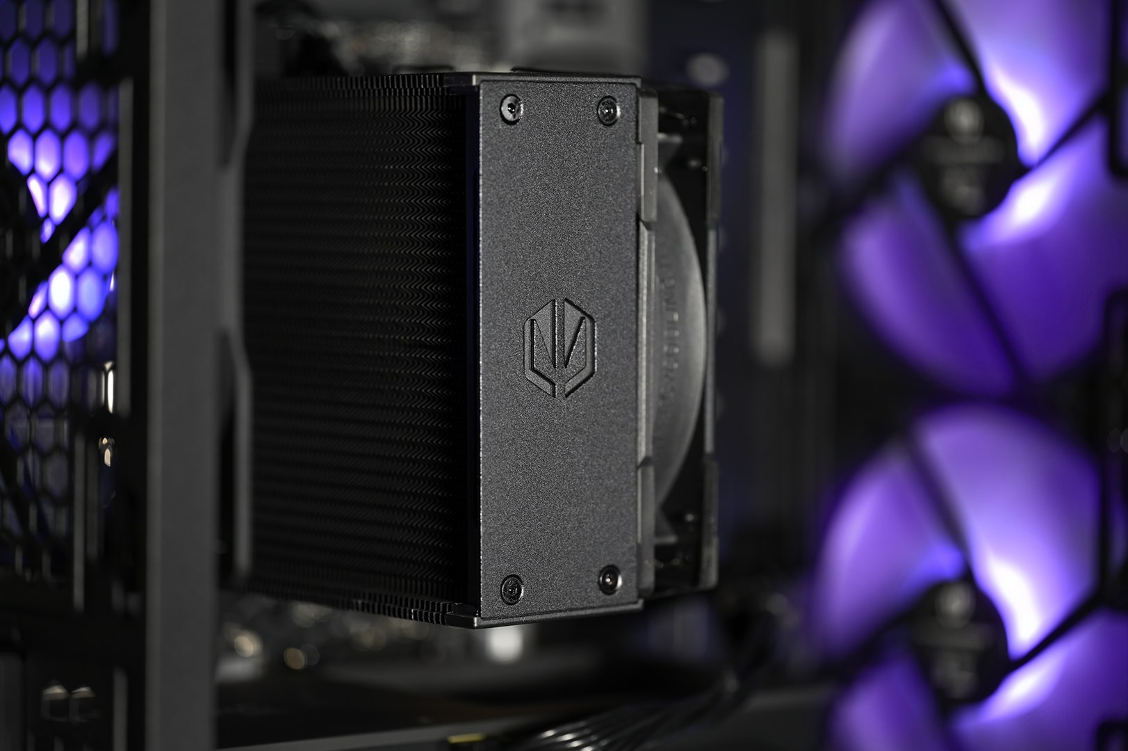 Zbliżenie czarnego chłodzenia procesora. Chłodzenie ma logo i jest zamontowane w obudowie komputera z fioletowymi światłami.