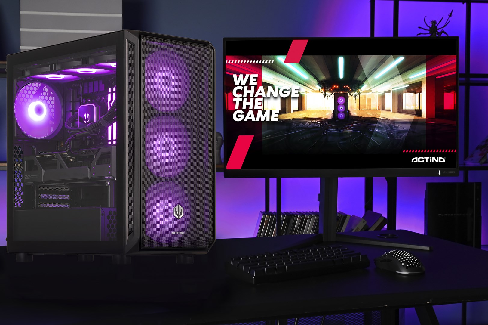 Komputer do gier z monitorem wyświetlającym 'We change the game'. Klawiatura, mysz i konsola na stole. Fioletowe światła.