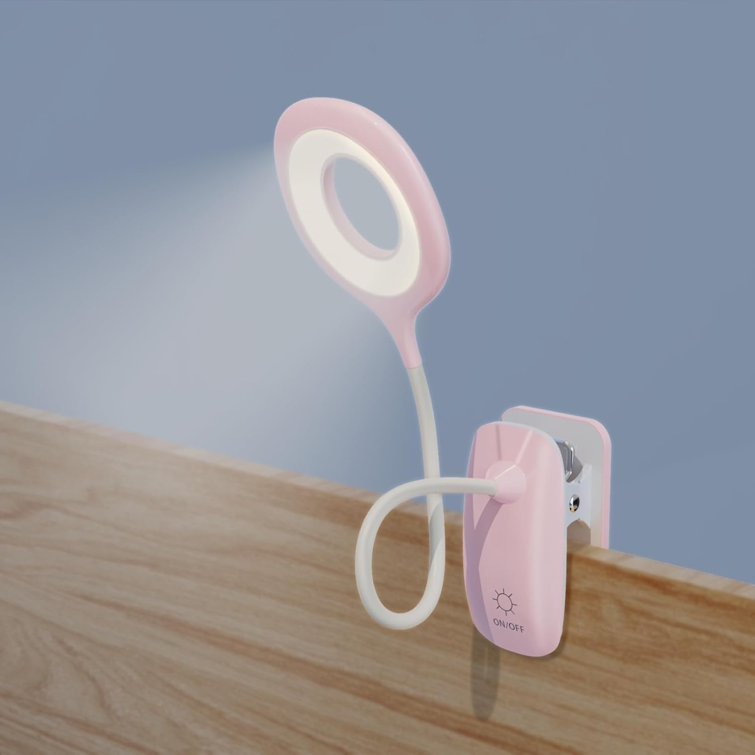 Eine rosa-weiße LED-Schreibtischlampe ist an einer Holzoberfläche befestigt. Die Lampe ist an und wirft Licht. Der Hintergrund ist hellblau.