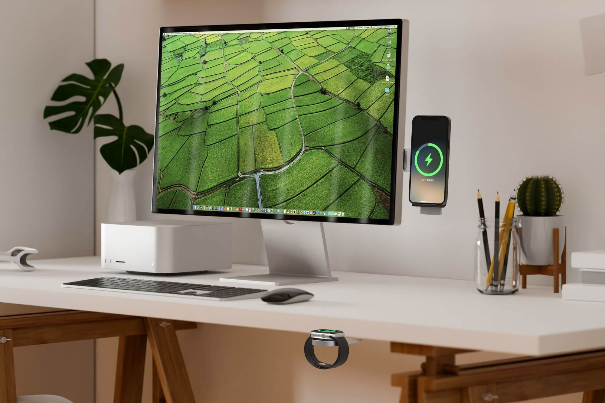 Ein Schreibtisch mit Computer, Telefon und Uhr. Der Computer zeigt ein grünes Feld. Ein Telefon wird geladen. Ein Kaktus und Bleistifte sind vorhanden.