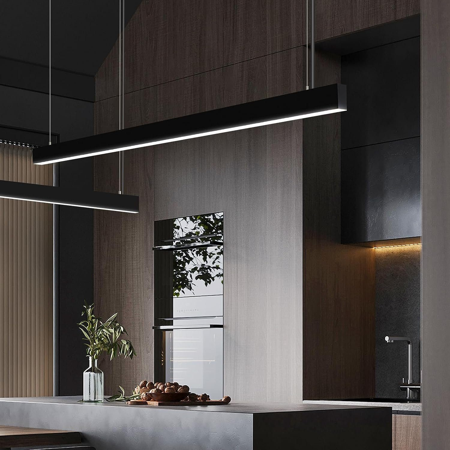Eine moderne Küche mit schwarzen, rechteckigen Lichtern, die von der Decke hängen. Eine Arbeitsplatte mit Vase und Schüssel mit Nüssen im Vordergrund.