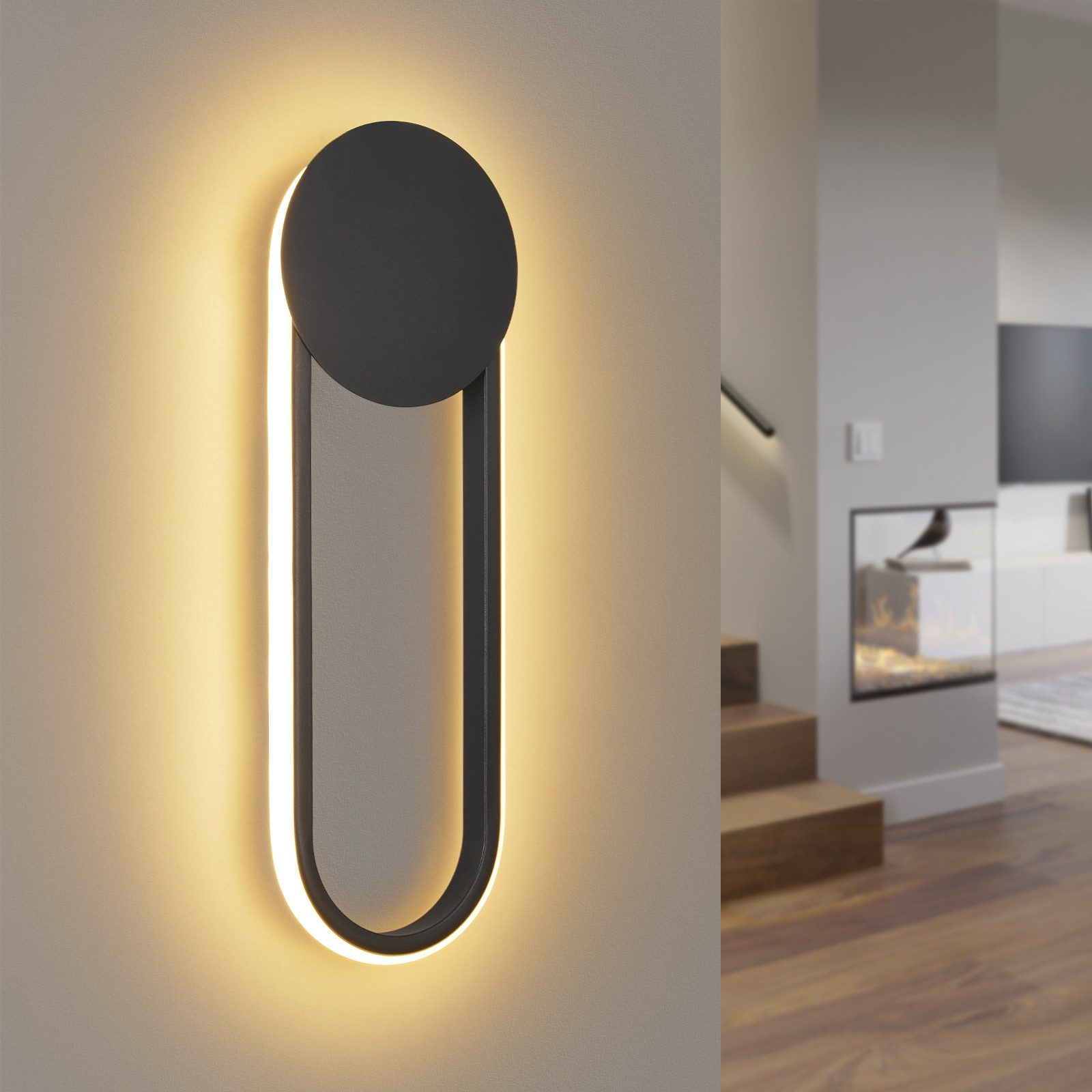 Una lampada da parete moderna con una parte superiore circolare nera e un corpo ovale illuminato su un muro beige. Un camino sullo sfondo.