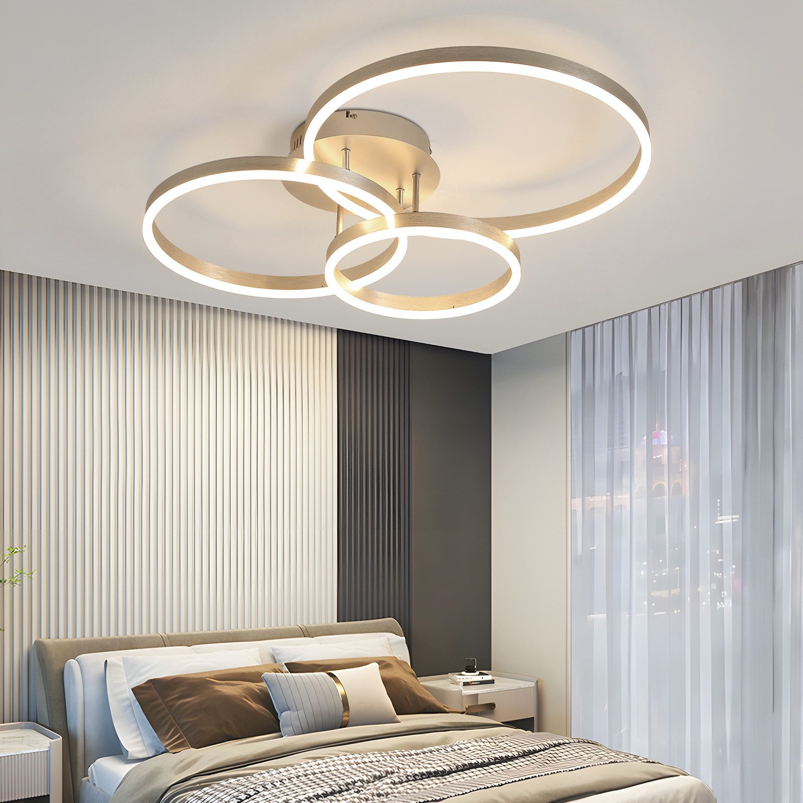 Una camera da letto con una moderna plafoniera, un letto e una parete decorativa. La luce ha tre anelli collegati.