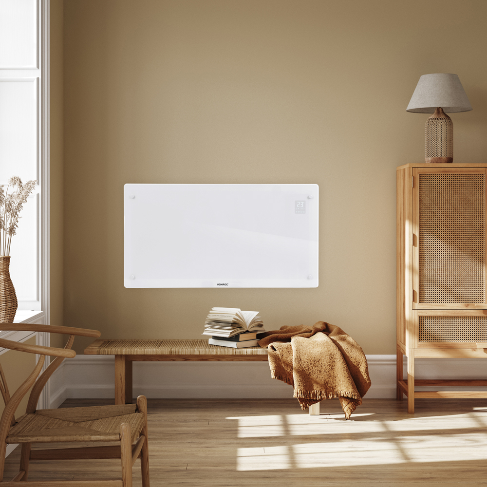 A white heater hangs on a beige wall. A bench with books and a blanket is below. A cabinet and lamp are to the right.