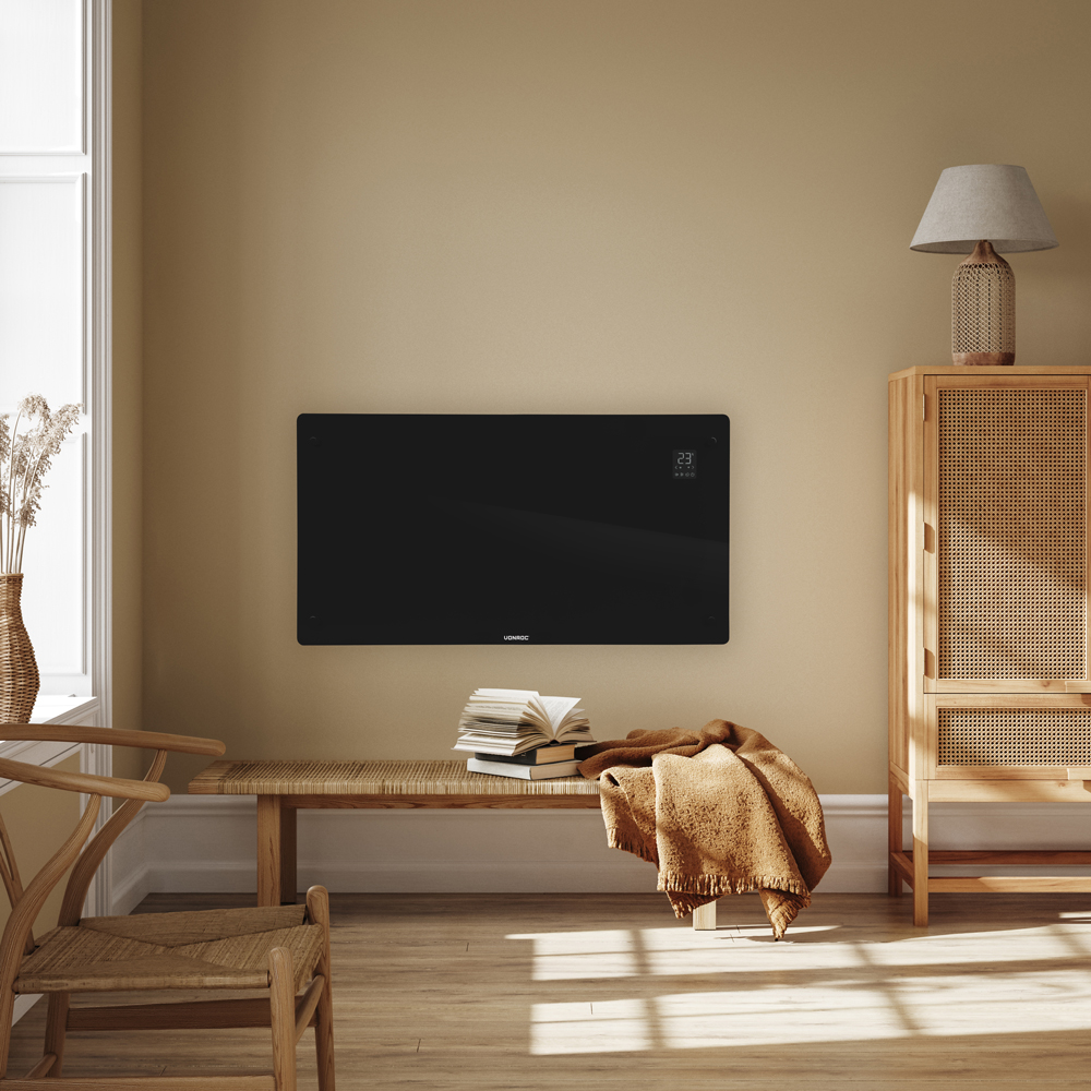 A modern living room with a black heater, bench, wooden furniture, and a window. A blanket and books are on the bench.