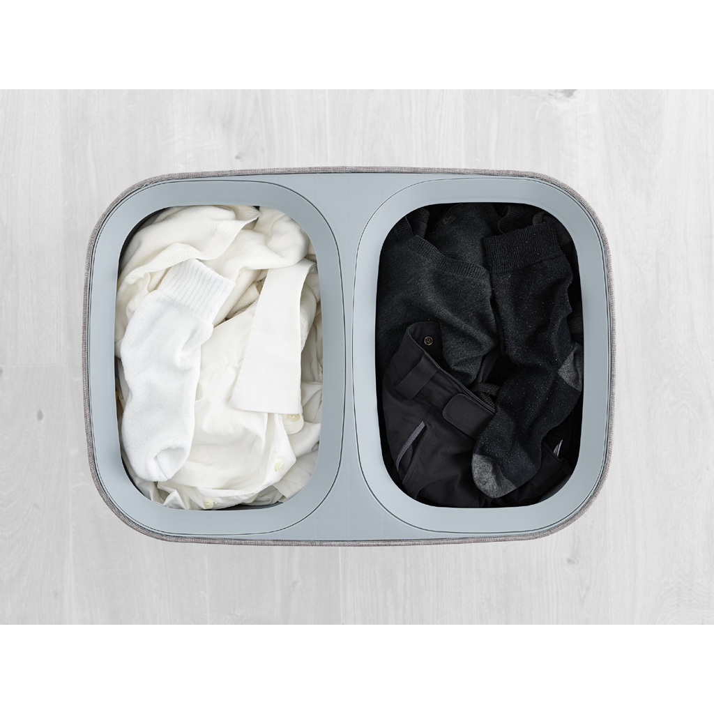 Una cesta de ropa con dos compartimentos. Un lado contiene ropa blanca, el otro ropa negra.
