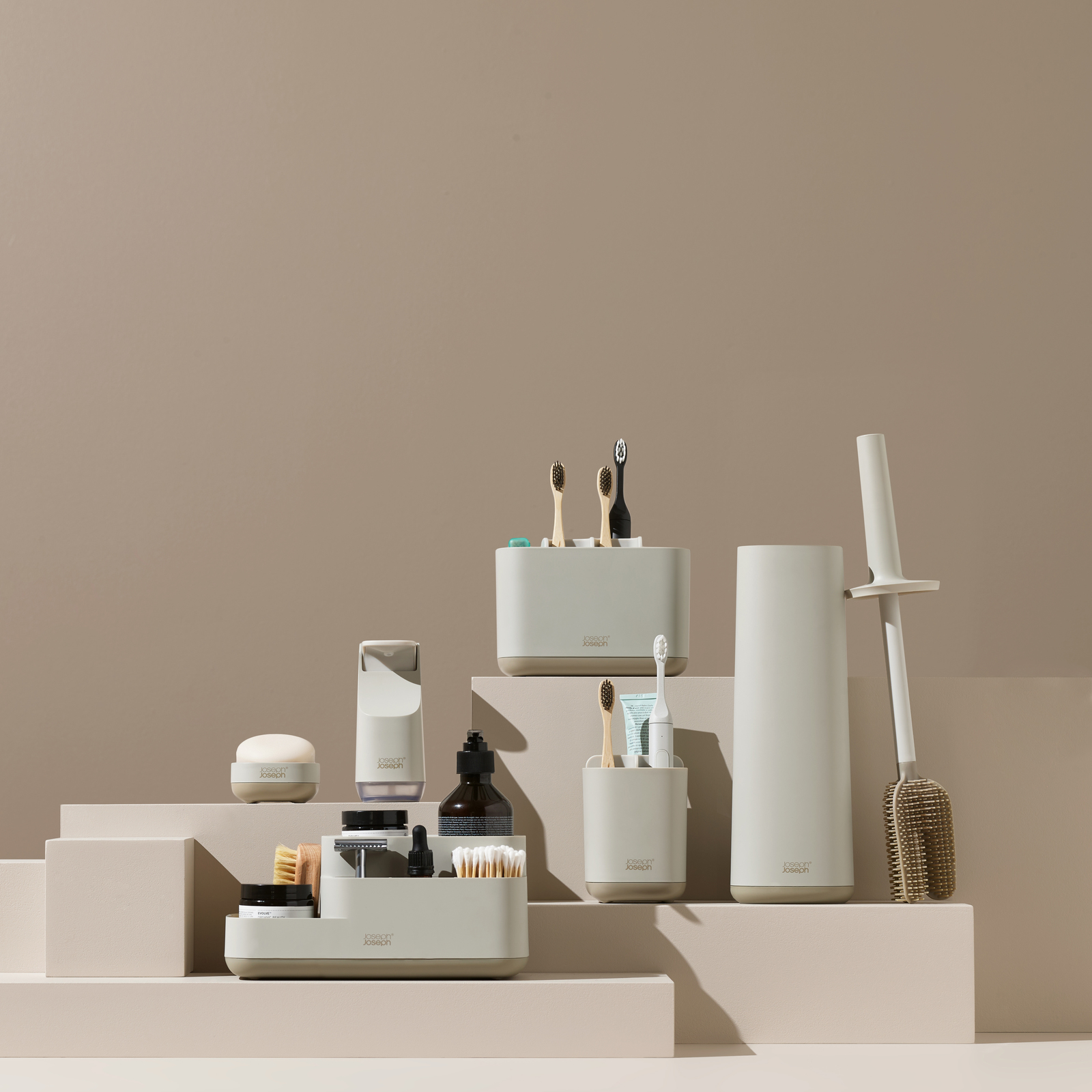 Accesorios de baño: porta cepillos de dientes, dispensador de jabón, cepillo de inodoro y otros artículos, todos en tonos beige y blanco.