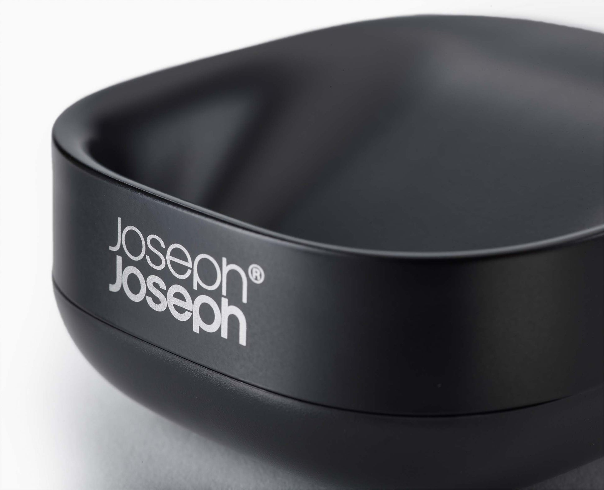 Primer plano de un jabonera ovalada negra. El nombre de la marca 'Joseph Joseph' es visible en el lateral con letras blancas.