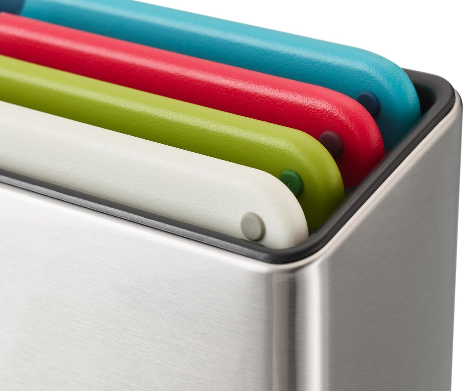 Tablas de cortar coloridas en un soporte metálico. Las tablas son azules, rojas, verdes y blancas. El soporte tiene un acabado metálico cepillado.