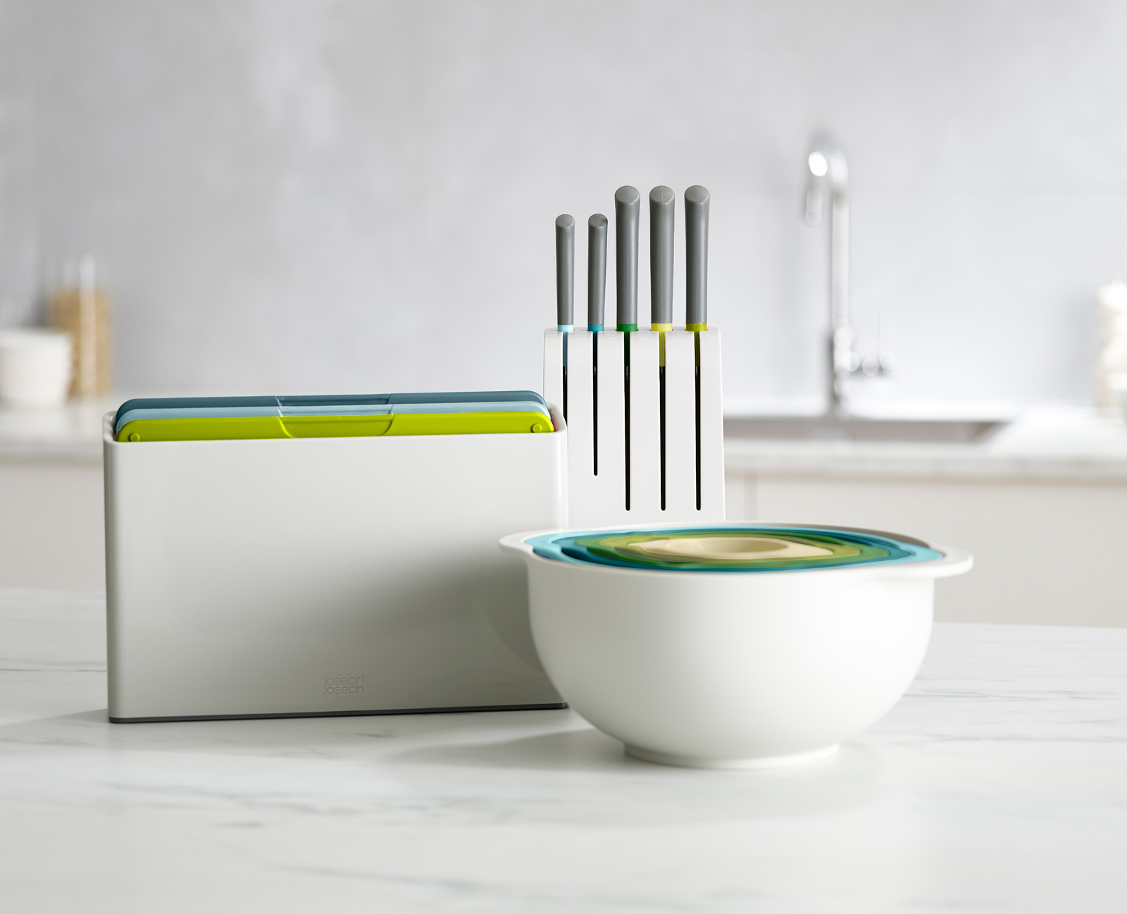 Juego de cocina con cuencos blancos, cuchillos y tablas de cortar. Cuencos anidados, cuchillos en un soporte y tablas en una caja.