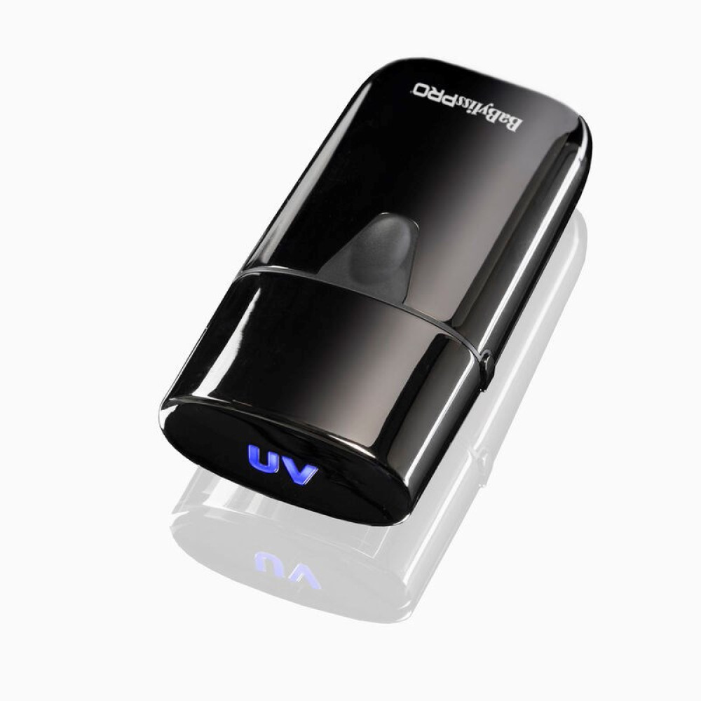 Una lampada per unghie UV BabylissPRO nera, con un display a luce UV blu, che si riflette su una superficie bianca.