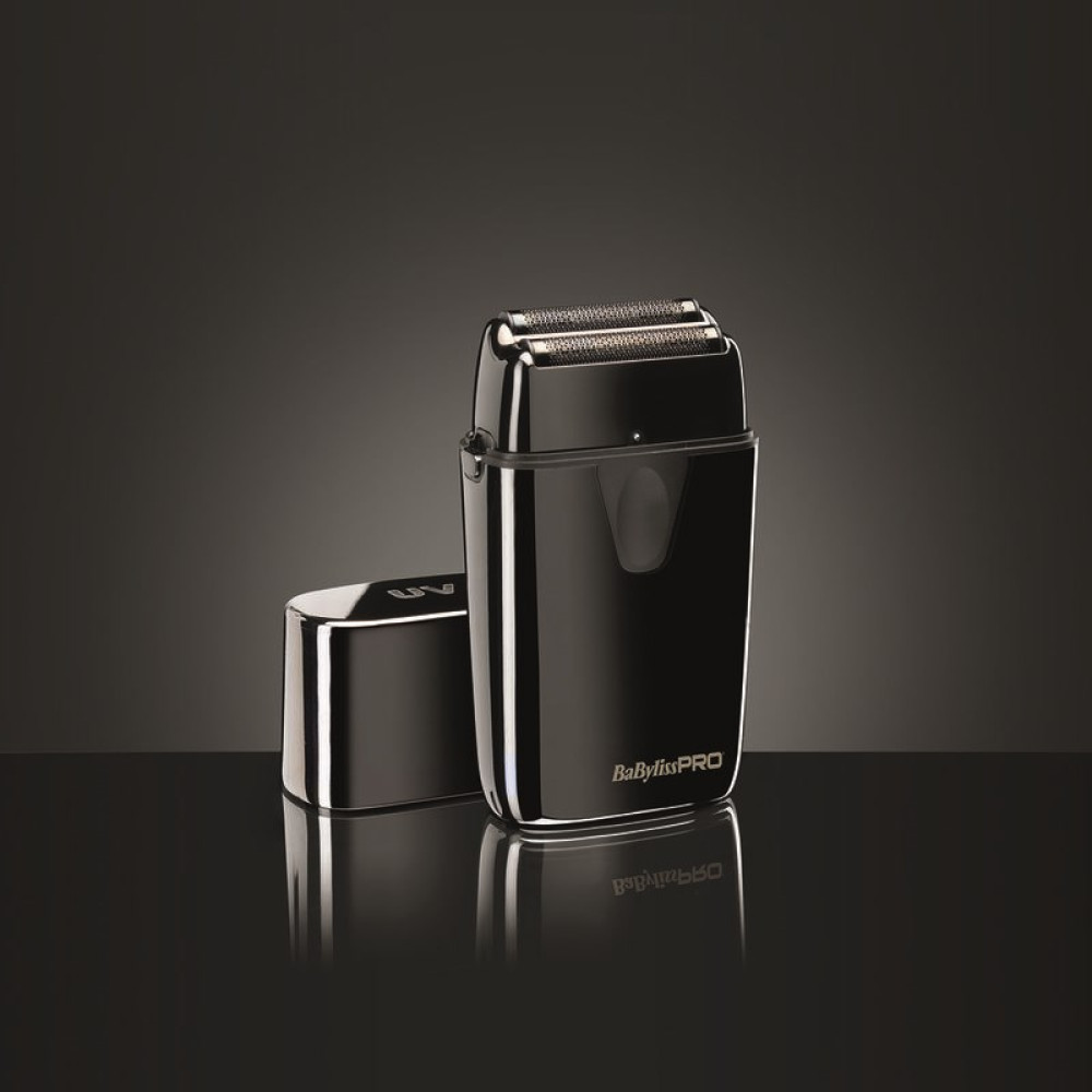 Un rasoio elettrico nero con il suo cappuccio rimosso è su una superficie riflettente. Lo sfondo è grigio scuro.