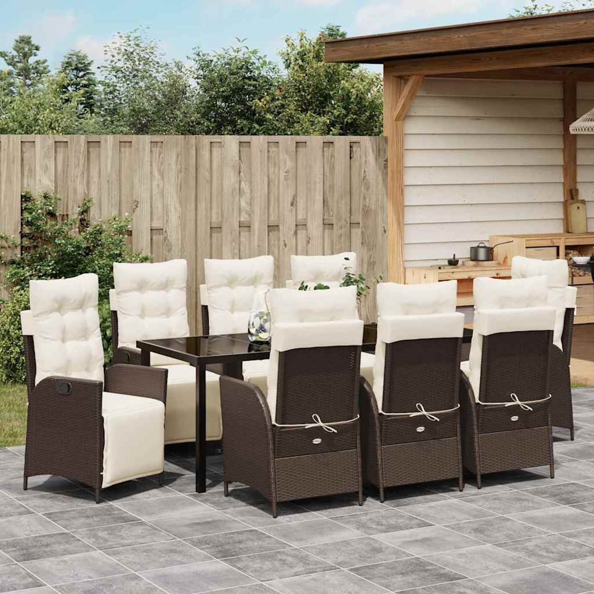 Essgruppe im Freien mit dunklem Tisch, acht braunen Stühlen mit cremefarbenen Kissen, auf einer gefliesten Terrasse, mit Holzzaun im Hintergrund.