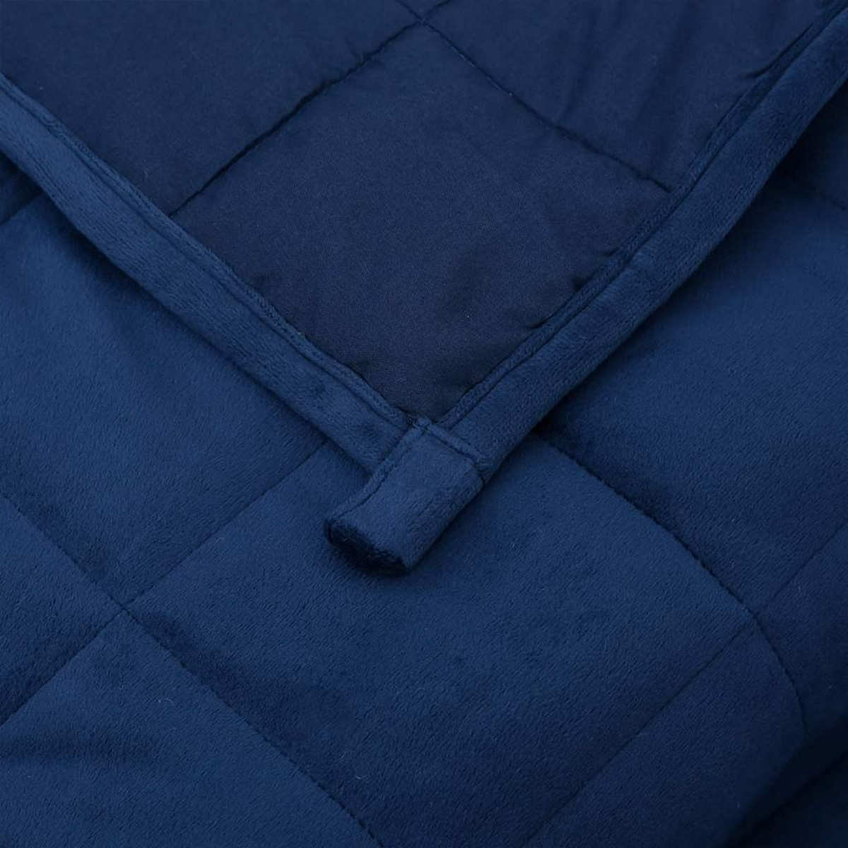 Nahaufnahme einer marineblauen, gesteppten Decke. Die Decke ist gefaltet und zeigt eine strukturierte Oberfläche und einen dunkleren, glatten Stoff.