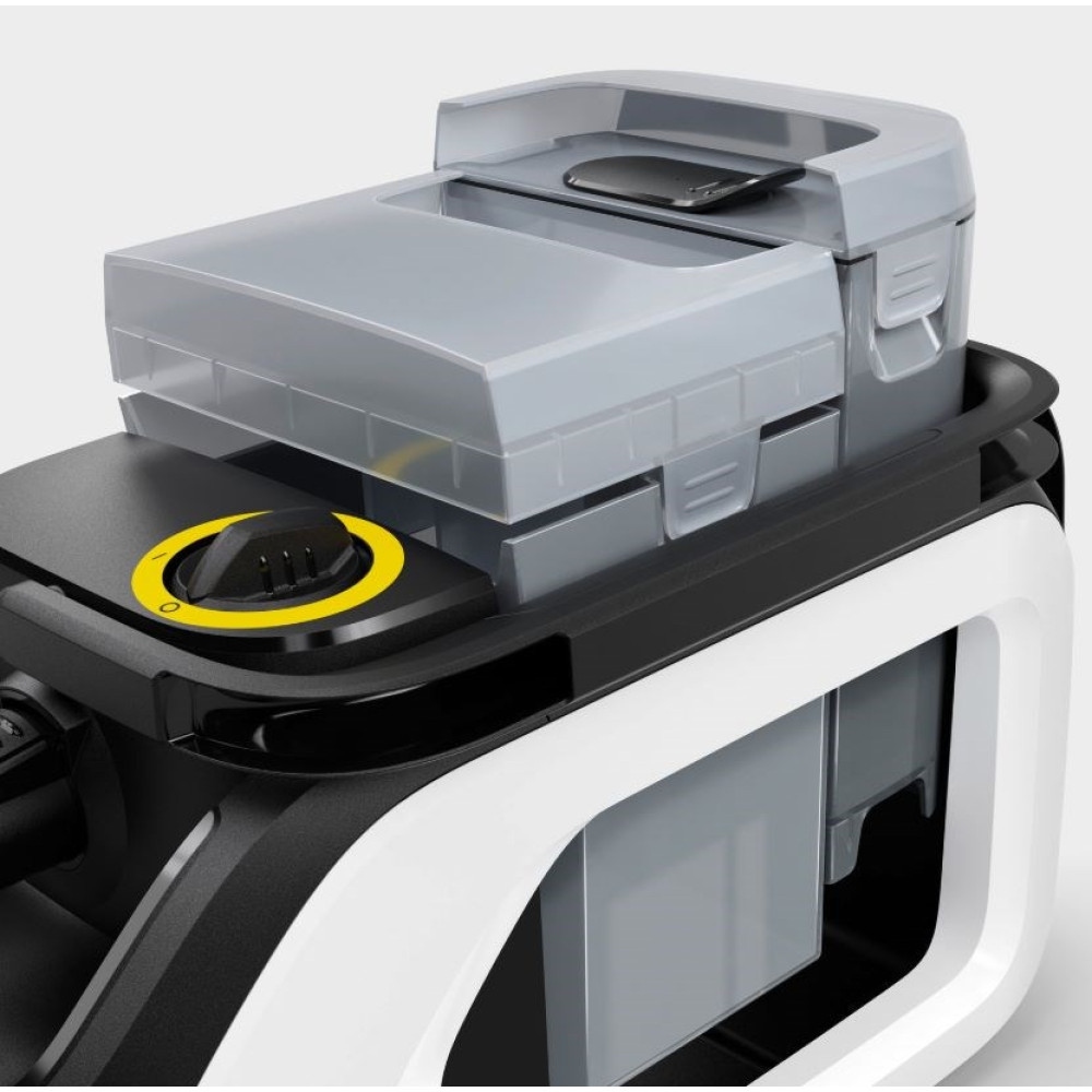 Zbliżenie myjki ciśnieniowej. Szary pojemnik z czarną pokrywą. Biała i czarna rama. Żółty detal tarczy.