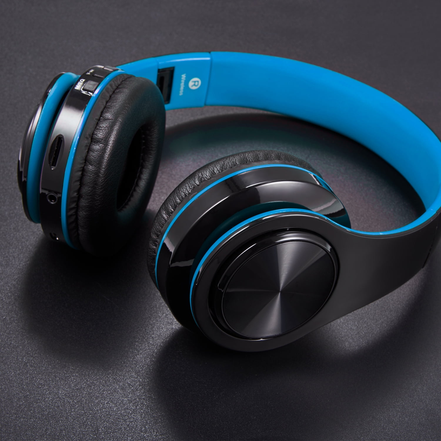 Schwarze und blaue kabellose Kopfhörer auf einer schwarzen Oberfläche. Die Kopfhörer haben ein blaues Stirnband und schwarze Ohrmuscheln.
