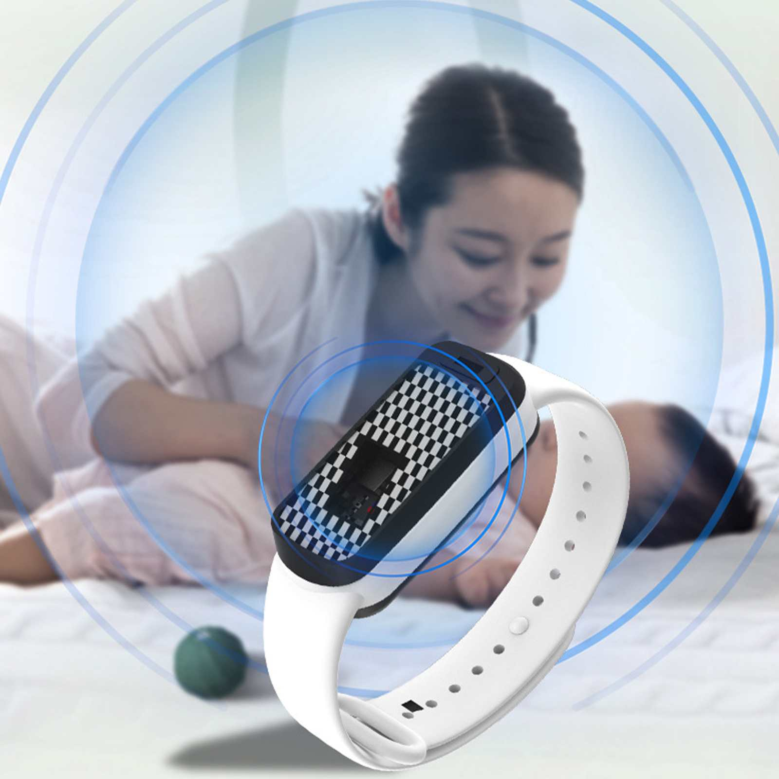 Eine weiße Smartwatch mit Schachbrettmuster auf einem Bett. Im Hintergrund sind eine Frau und ein Kind unscharf.