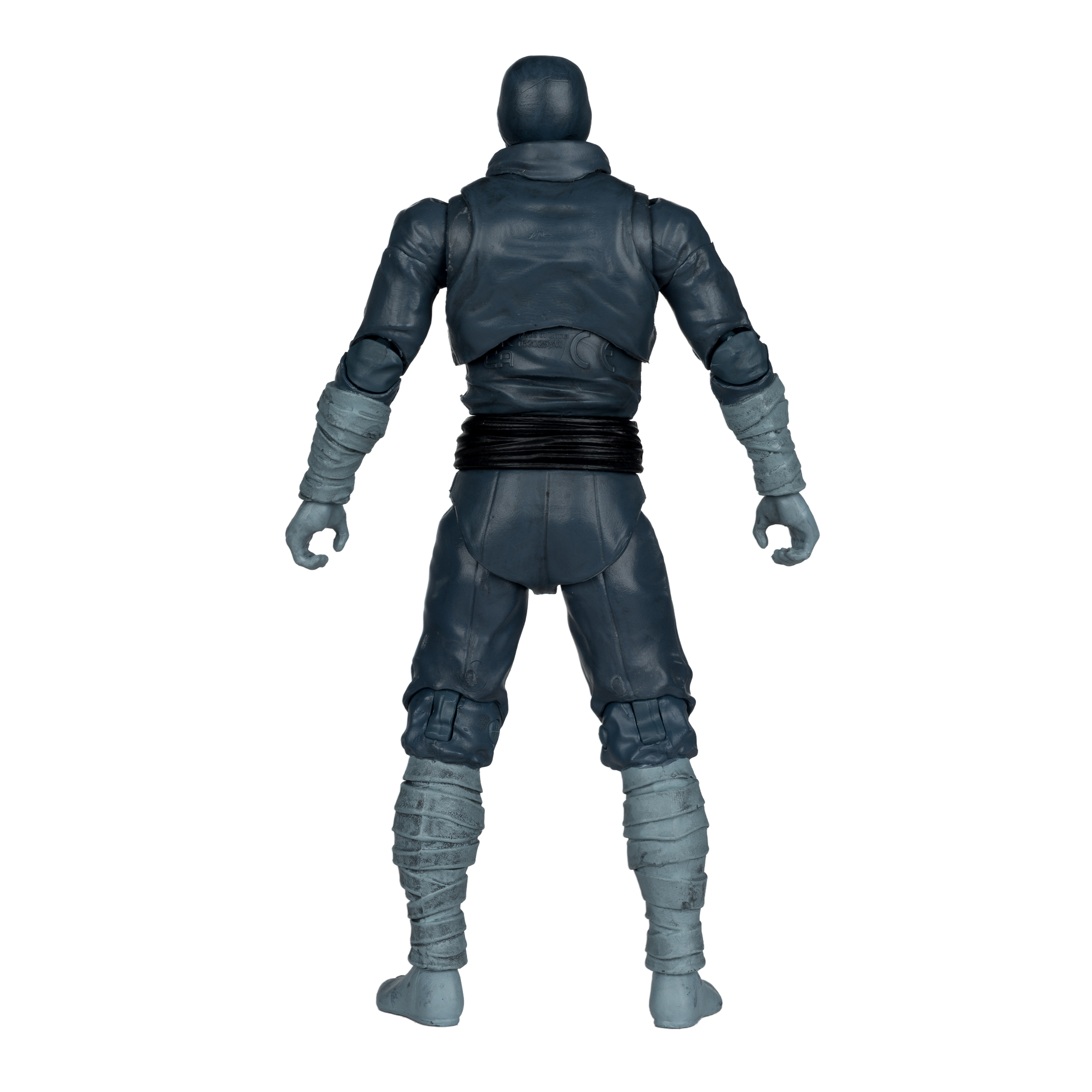 Una figura de acción ninja gris se ve por la espalda. Lleva capucha, chaqueta, pantalones y vendajes. El fondo es blanco.