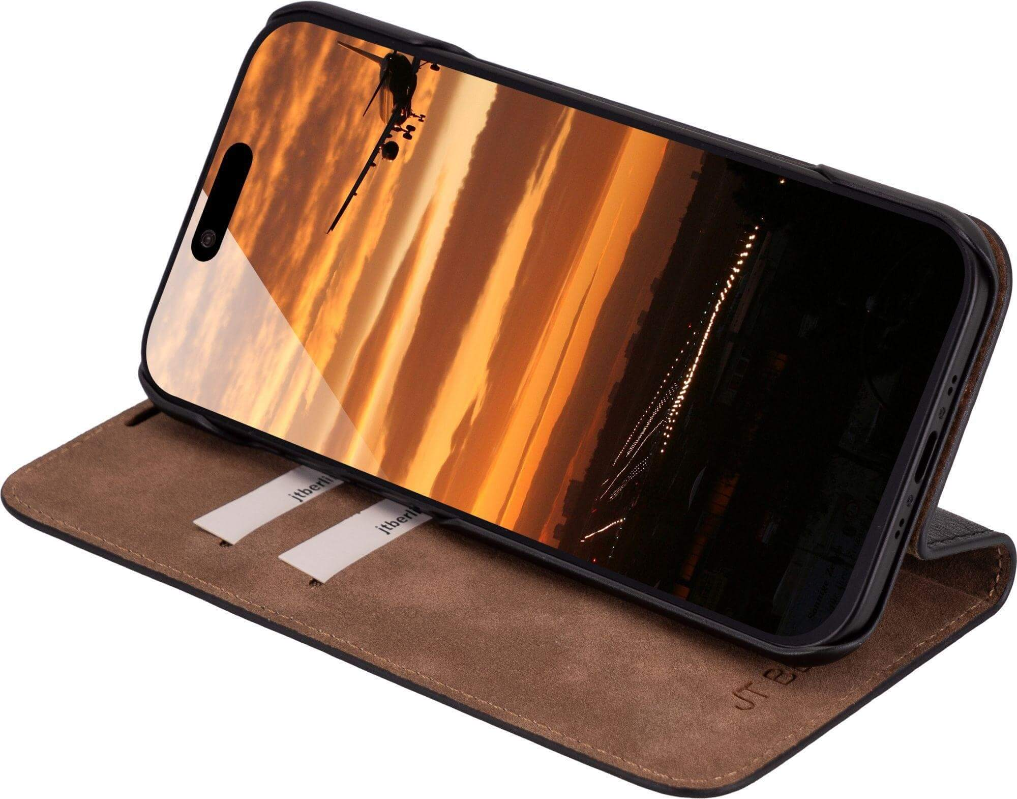 Telefon in Hülle mit Sonnenuntergang und Flugzeug. Die Hülle ist auf einer braunen Oberfläche geöffnet, mit jtberli beschriftet.