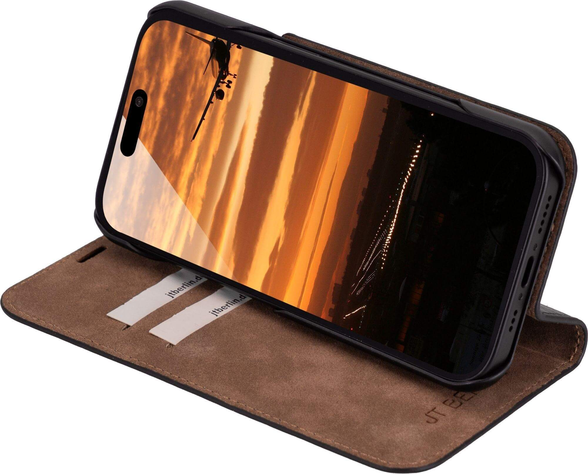 Telefon in Lederhülle zeigt Sonnenuntergang mit Flugzeug. Hülle braun, Telefon schwarz.