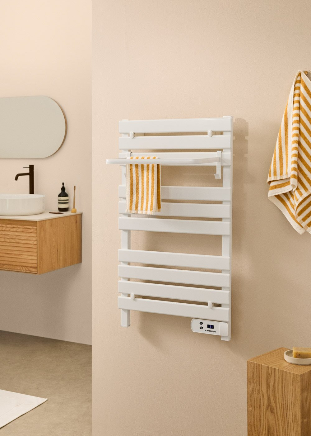 Escena de baño con un calentador de toallas blanco, toallas a rayas, un espejo y elementos de madera. Paredes y suelo beige.