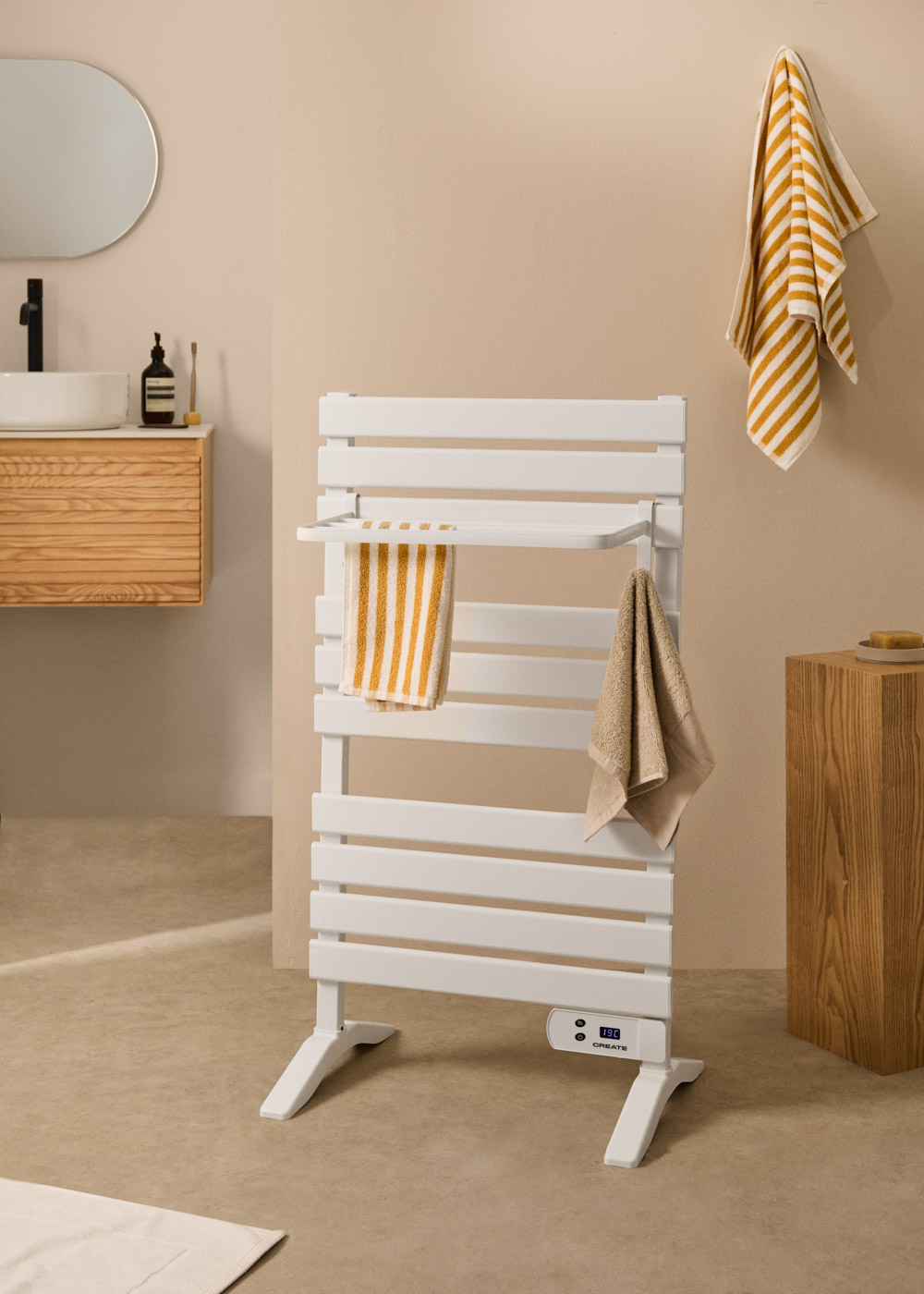 Un toallero blanco con toallas en un baño. Un espejo y un mueble de madera están a la izquierda.