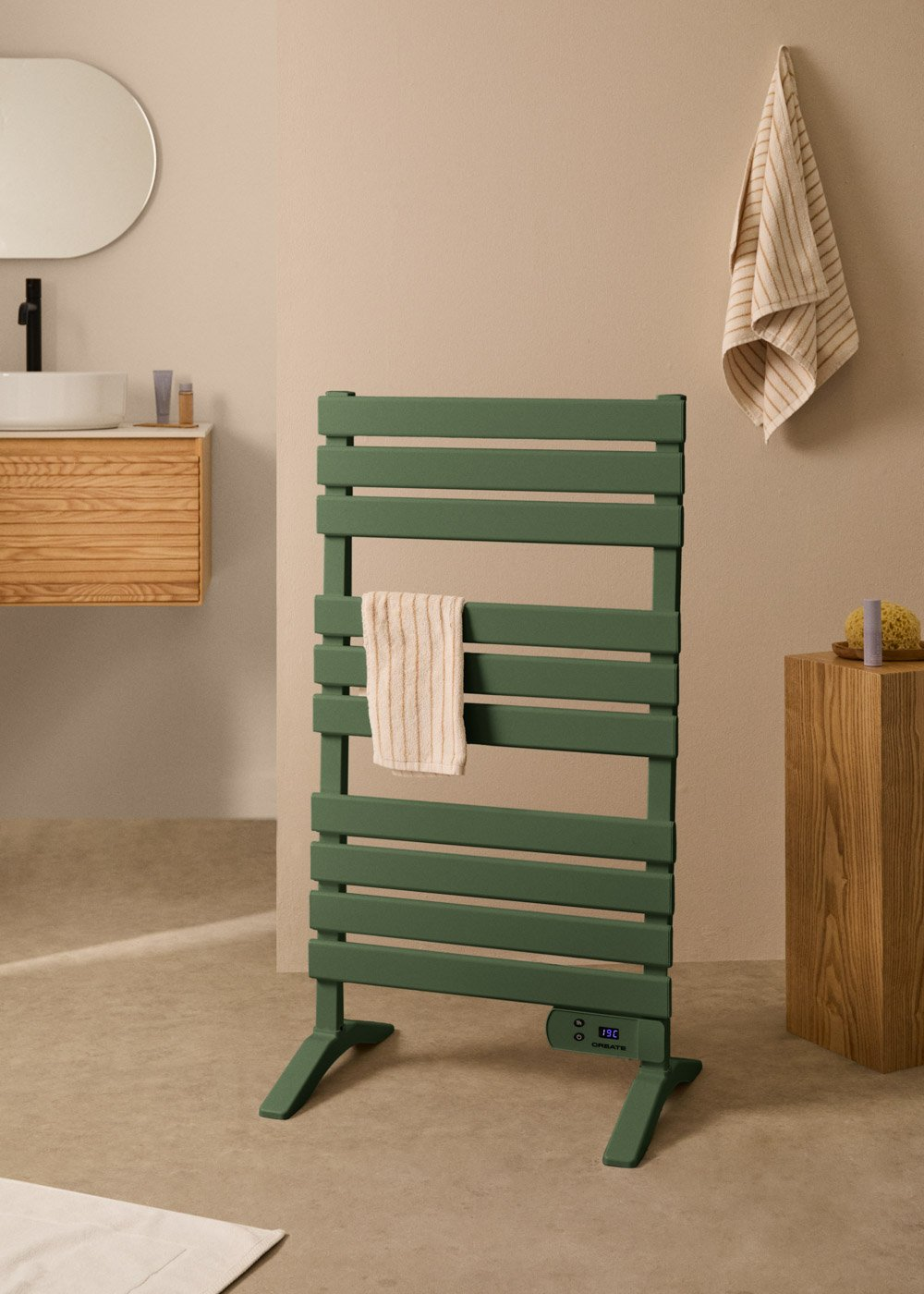 Un calienta toallas verde con una toalla colgada. Fondo de baño con espejo y mueble de madera.