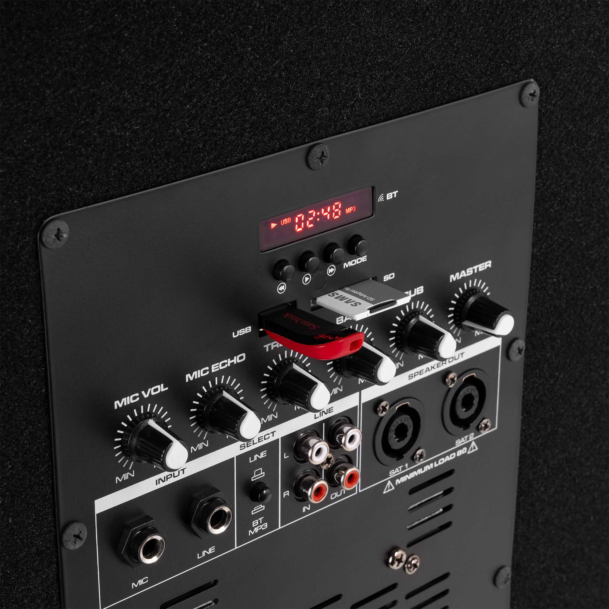 Panel negro de dispositivo de audio con botones, perillas y puertos. Tiene una pantalla roja y una unidad USB insertada.