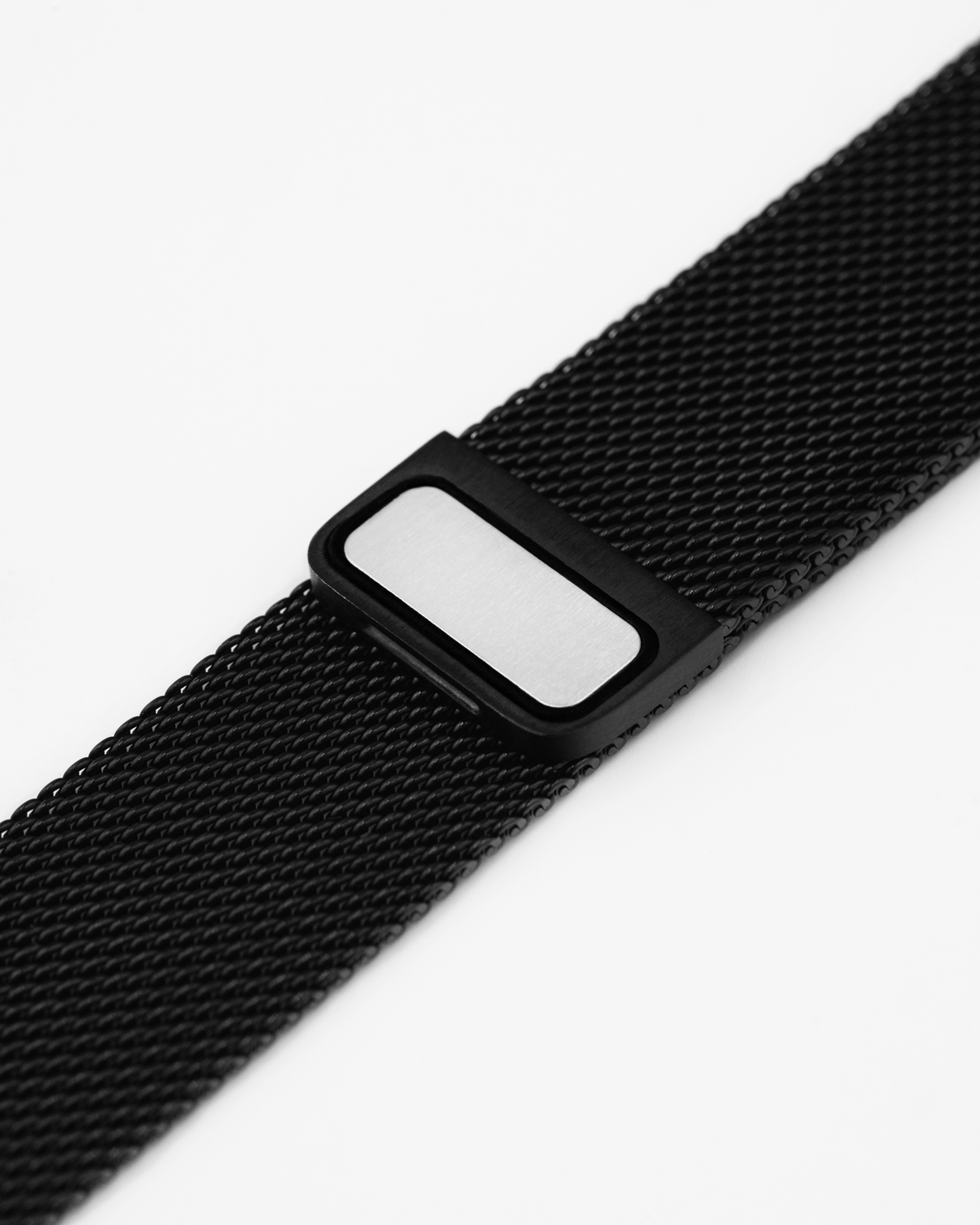 Nahaufnahme eines schwarzen Uhrenarmbands. Das Armband besteht aus einem Netzmaterial mit einem rechteckigen Verschluss. Der Hintergrund ist weiß.