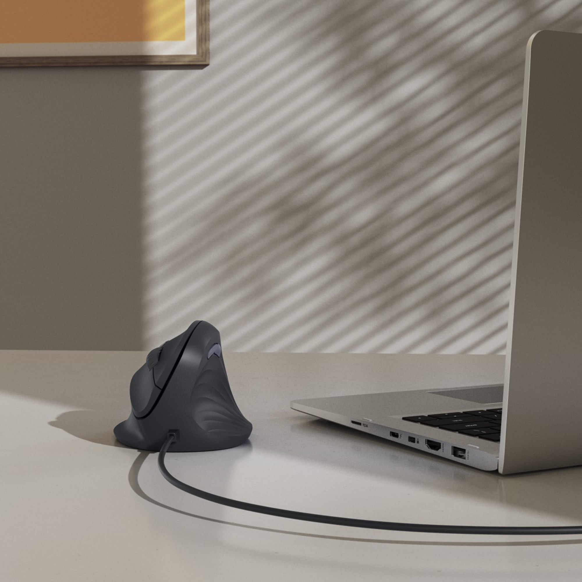 Ergonomische Maus mit Laptop verbunden. Schatten von Jalousien an der Wand. Bilderrahmen an der Wand.