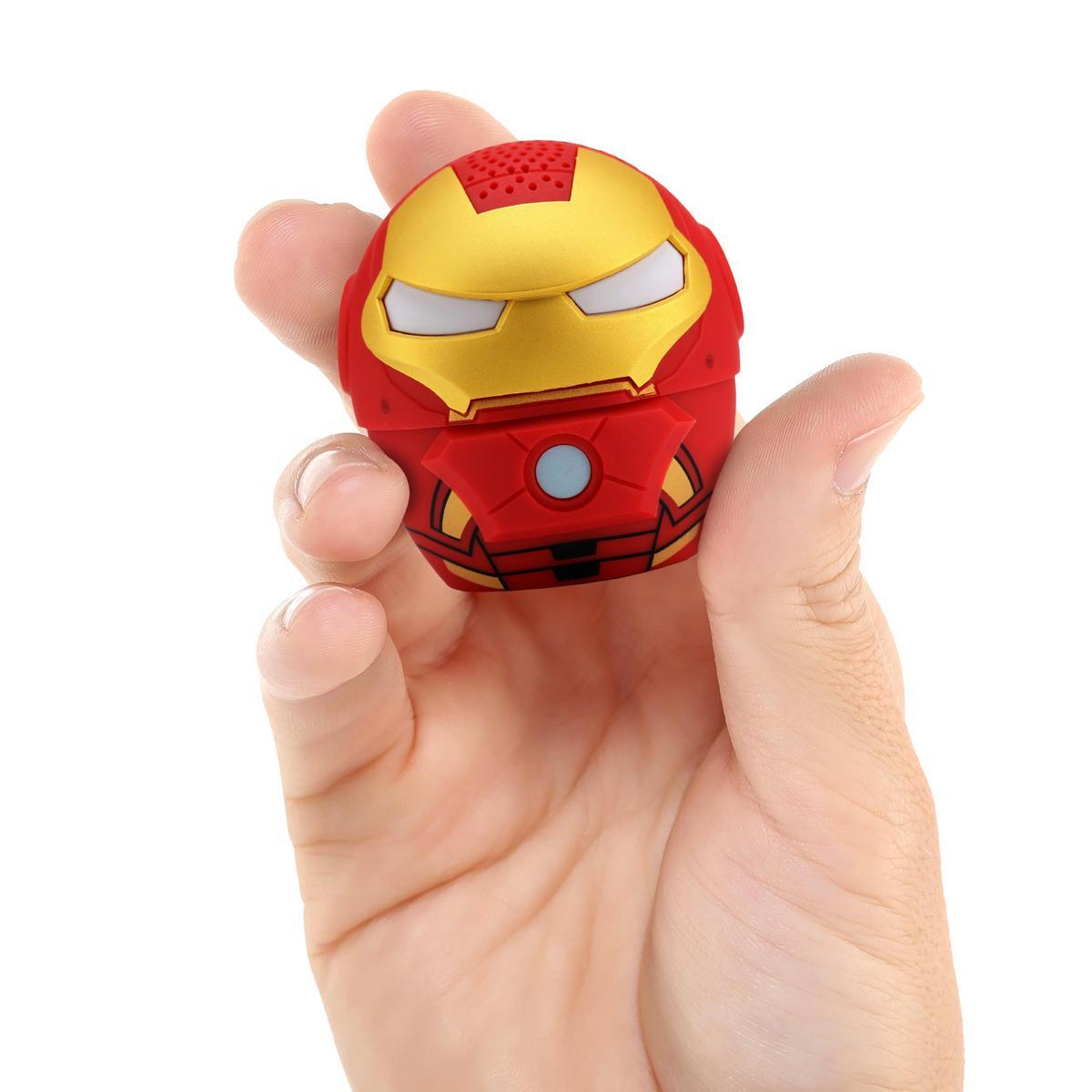 Bir el, kırmızı ve altın rengi bir Iron Man hoparlörünü tutuyor. Hoparlör yuvarlak ve yüz tasarımlı. Arka plan beyazdır.