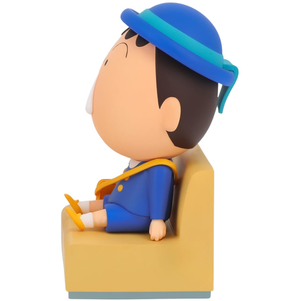 Eine Zeichentrickfigur eines Jungen in blauer Uniform und Hut sitzt auf einem gelben Sitz. Er hat eine gelbe Tasche und schaut nach links.