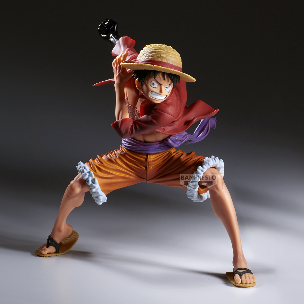 Eine Figur eines Manga-Charakters in Aktion. Er trägt einen Strohhut, ein rotes Hemd, orange Shorts und Sandalen. Bereit zum Kämpfen.