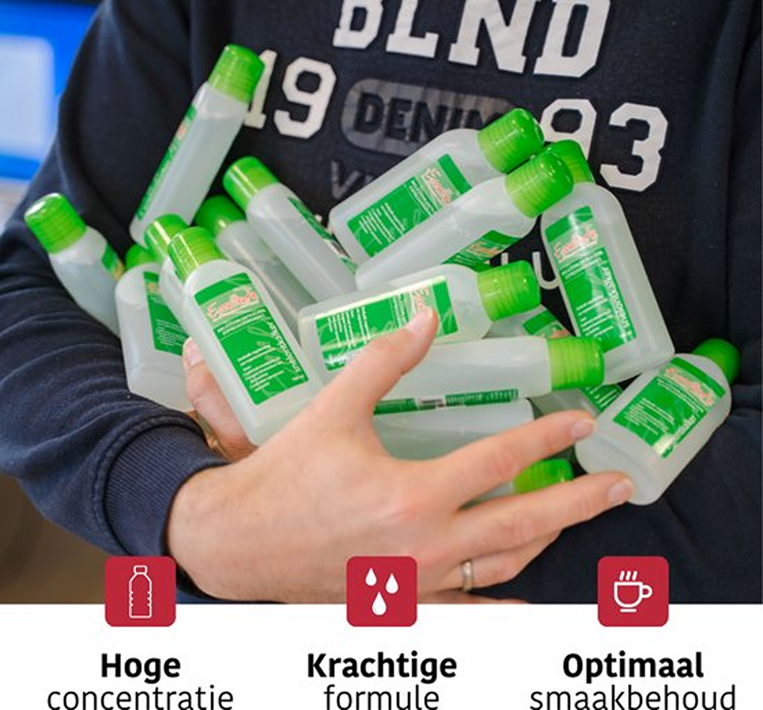 A person holds multiple bottles with green caps and labels. The bottles are clear with a white liquid. They are in front of a dark blue shirt.
