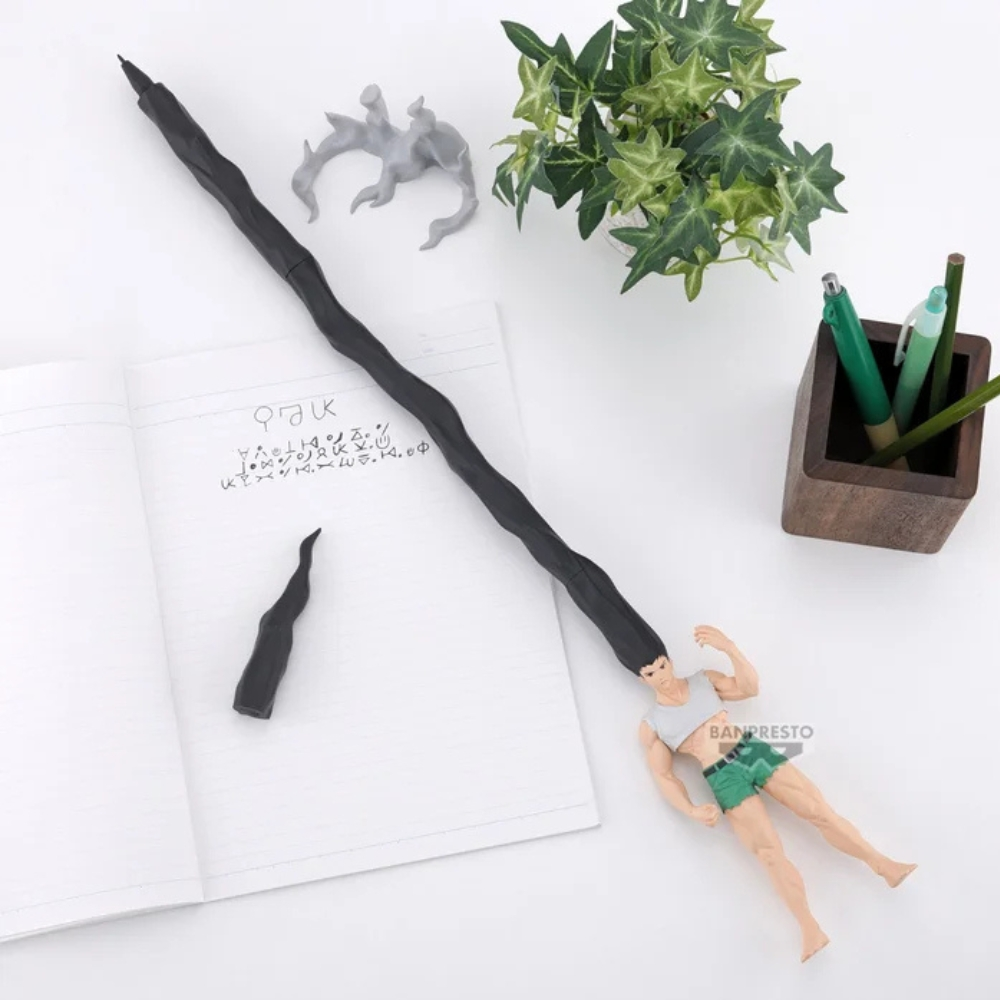Ein Stift mit langem, schwarzem Körper, eine Figur eines Mannes in Shorts, ein Notizbuch, eine Pflanze und einige Stifte in einem Holzhalter liegen auf weißem Untergrund.