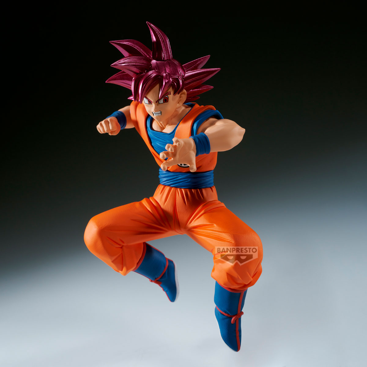 Una figura de Goku en pose de acción. Tiene pelo rosa puntiagudo, atuendo naranja y azul, y está saltando con expresión concentrada.