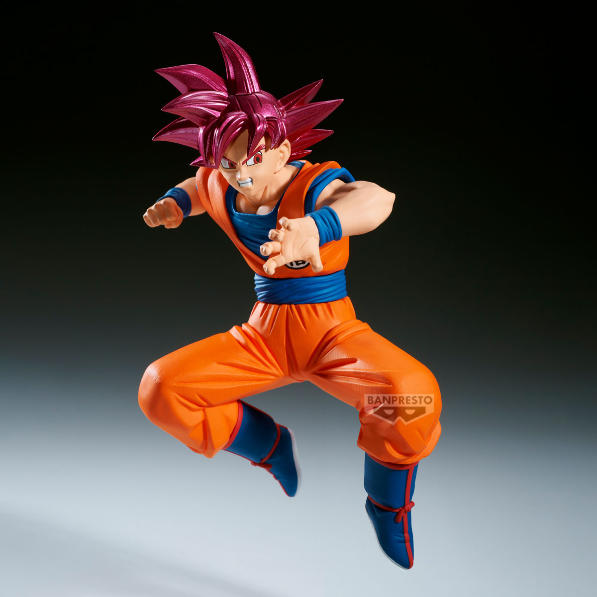 Una figura de Goku en pose dinámica. Viste un traje naranja con detalles azules. Su cabello es puntiagudo y rosa, y está en plena acción.