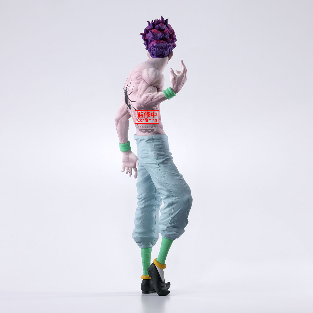 Una statuetta di un personaggio con capelli viola e pantaloni azzurri. Ha un tatuaggio a forma di ragno e polsini verdi. Scarpe nere con dettagli gialli.