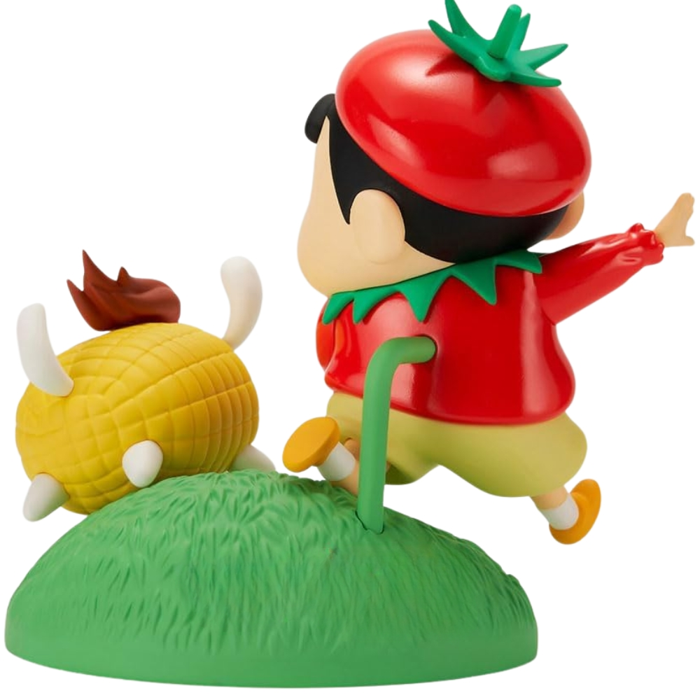 Una statuetta di un ragazzo in costume da pomodoro che salta su una collina verde accanto a un personaggio a forma di mais.