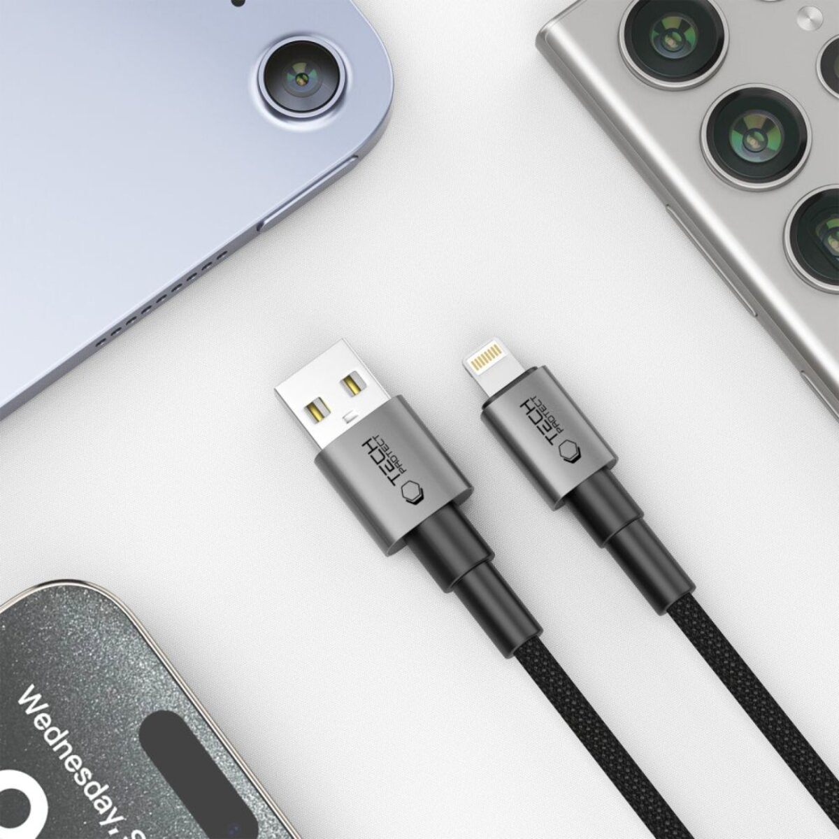 Deux câbles de charge noirs avec connecteurs gris se trouvent près de deux téléphones et une tablette.