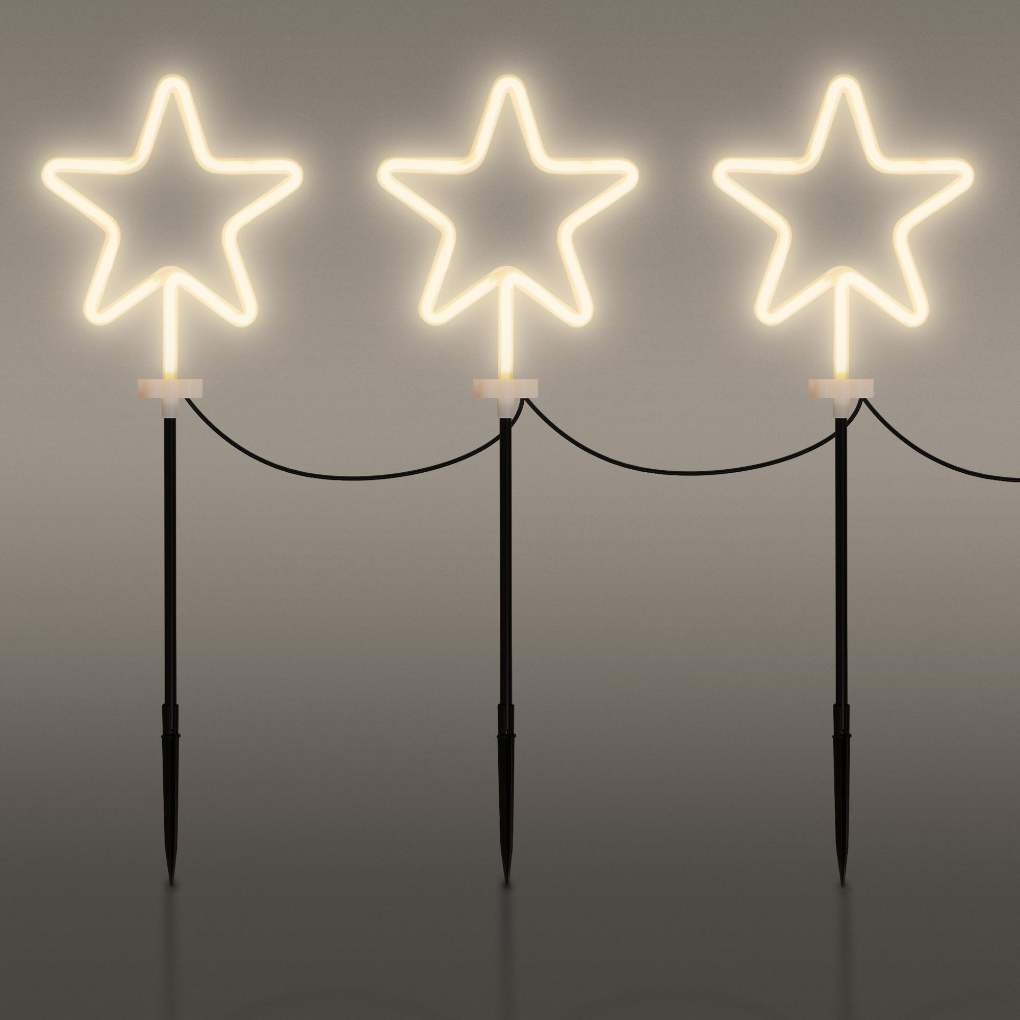 Drei leuchtende sternförmige Lichter, cremefarben, auf schwarzen Pfählen angeordnet. Drähte verbinden die Lichter, alles auf grauem Hintergrund.